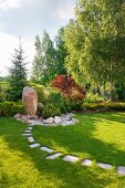 Parkähnlicher Garten mit Findling und Steinplattenweg im Rasen