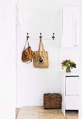 Nostalgic wall hook strip with hanging pockets next to a white cupboard