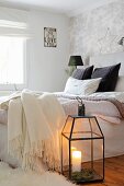 Candle lantern and fleecy blankets in cosy bedroom