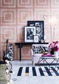 Coffee table in polyhedron form and maritime woven carpet in front of a sofa, black and white decorative objects, wall graphics with pastel colored squares