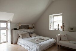 Scatter cushions on double bed in bedroom with sloping ceiling