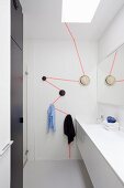 Black pegs connected by neon zigzag line in white designer bathroom