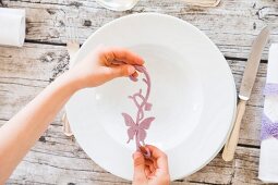 Person decorating place setting with felt butterfly (top view)