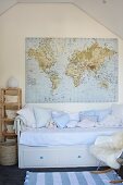 Hellblaue Kissen auf Kinderbett mit integrierten Schubladen an Giebelwand mit aufgehängter Weltkarte im Dachzimmer