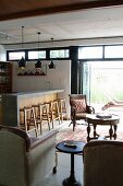 Gemütlicher Loungebereich mit Antikmöbeln und Küchentheke mit passenden Barhockern, Blick auf Terrasse