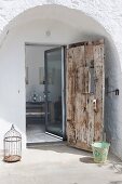 Rustic wooden front door and modern glass door in arched doorway of stone house
