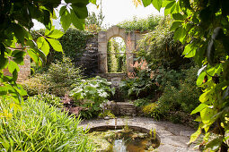 Round pool surrounded by stone terrace in flowering garden