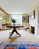 Antiker, rollbarer Tisch in Wohnzimmer mit hellgelb getönten Wänden und gerahmten Bildern