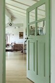 Half-open interior door painted pastel green with view into sleeping area in open-plan converted attic