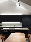 Blaugraue Designerküche mit Küchentheke, indirekter Beleuchtung und Edelholztisch im Dachgeschoss