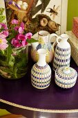 Kunsthandwerkliche traditionelle Vasen auf violetter Tischplatte mit Blumenschmuck