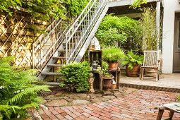 Terrace with plants, potted plants, stone paving and galvanised external staircase leading to balcony