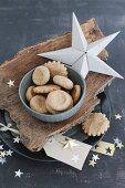 Christmas biscuits in bowl on piece of bark and stars hand-crafted from paper and gold foil