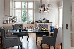 Postmoderne Sessel mit grauem Bezug um Tisch in moderner Küche