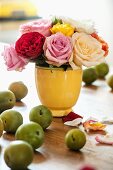 Roses in vintage vase and green apples on wooden table