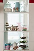 Decorative, vintage-style kitchen utensils on white shelves in window