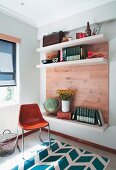 Shell chair next to shelving with wooden back wall and white shelves