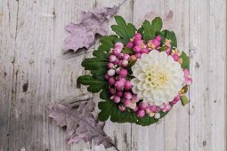 Bouquet with white dahlia and snowberries on rustic wooden surface