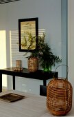 Wicker lantern and black console table against pale blue wall