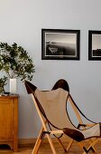 Classic canvas chair with wooden frame in front of framed photos on wall painted pale blue
