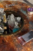 Champagne and crystal decanters in sunken area integrated into centre of artistic round glass table