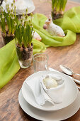Place setting with white Easter egg in napkin nest