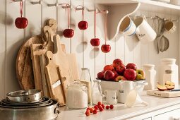 Fresh apples, baking ingredients and various kitchen utensils on dresser