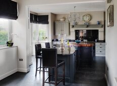 Free-standing counter and bar stools with black leather seats in open-plan, country-house-style kitchen