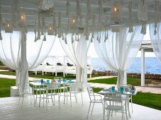 Set table on white wooden terrace with curtains and sea view