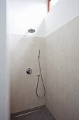 Moderner Duschbereich mit zeitgenössischer Armatur an sandfarben gefliester Wand und Kopfbrause