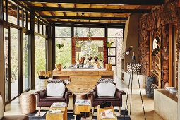 Brown leather armchairs in lounge area in front of dresser and dining set in Colonial-style open-plan interior