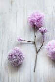 Twig with hand-made pompom flowers in lilac