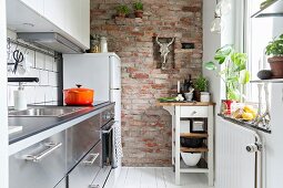 Schmale Küche mit Backsteinwand und Servierwagen