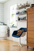 Retro-Drehstuhl unter Stringregal mit Geschirr, daneben Rollladenschrank aus Holz im Küchenbereich