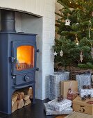 Gusseiserner Kamin mit Feuer in Nische, seitlich Weihnachtsbaum und Geschenke auf Boden