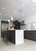 White kitchen counter and bar stools in modern fitted kitchen