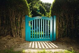 Blue-painted garden gate flanked by hedges