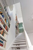 Blick eine Treppe hoch mit deckenhohen Bücherregalen