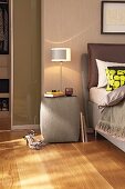 Table lamp on grey upholstered bedside table with glass top
