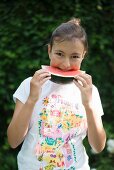 Mädchen isst Wassermelone im Garten