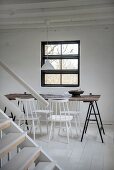 Schlichter Essplatz mit weiss lackierten Stühlen um Tisch, Holzplatte auf Metallböcken