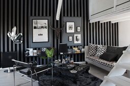 Wassily chair and black and white sofa in masculine interior with arrangement of framed pictures on grey and black striped wallpaper