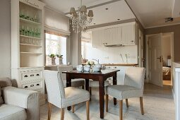 Pale upholstered dining chairs and dark brown wooden table in open-plan kitchen