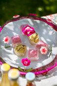 Colourful petit fours under mesh cake cover decorated with crocheted flowers on garden table