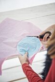 Girl cutting circles out of pastel tissue paper using template