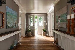 Console tables with curved legs against grey-painted walls in foyer of country house