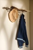 Straw hat and jacket hanging from coat rack hooks