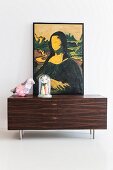 Sideboard mit verfremdetem Bildnis von 'Mona Lisa', Tischleuchte in Vogelform und Glashaube mit Vasen