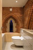 Bathroom with modern installations, brick wall and Gothic windows in converted church