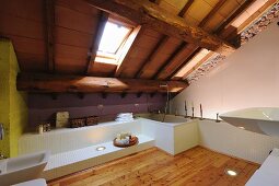 White installations, sloping ceiling with exposed wooden structure and skylight in modern bathroom with larch flooring
